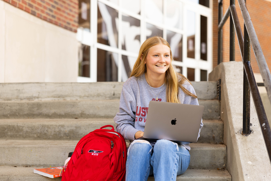 Student with laptop sitting outside